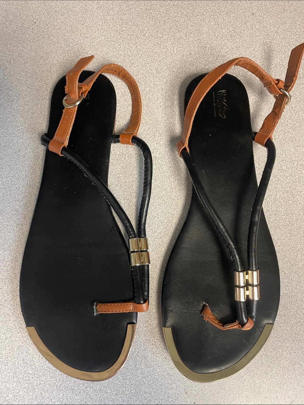 Black and brown t-strap sandals with gold accents